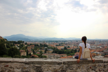 Fototapeta na wymiar Giovane donna seduta sulle mura di Bergamo alta, porta San Giacomo. Lombardia, Italia