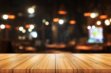 Empty wooden table top with blurred coffee shop or restaurant interior background. Abstract background can be used for display.