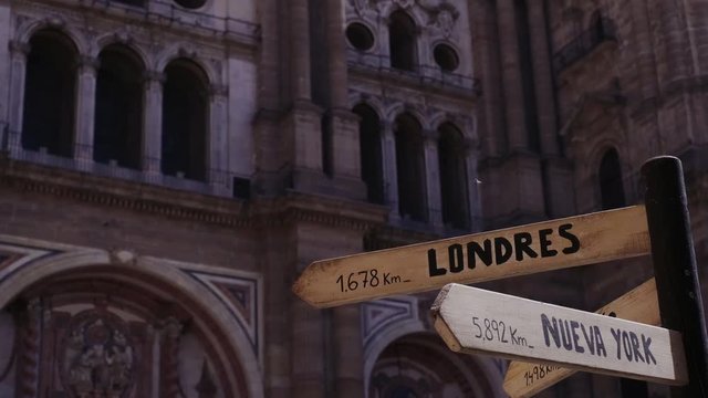 A wooden post with a road sign that points to London, Paris and New York 