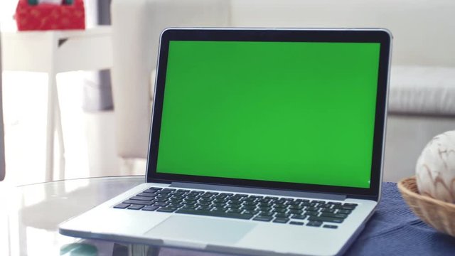 Laptop Computer Showing Green Chroma Key Screen Stands on a Desk in the Living Room. In the Background Cozy Living Room. Dolly Zoom out Shot. 4K