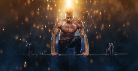Photo of strong muscular bodybuilder athletic man pumping up muscles with barbell on fire...