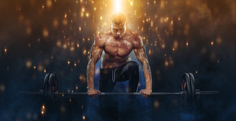 Photo of strong muscular bodybuilder athletic man pumping up muscles with barbell on fire...
