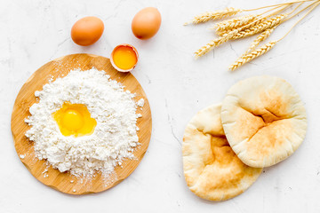 Make bread concept. Flat bread near wheat ears, flour and eggs on white background top view