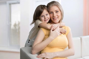 Mother and daughter hugging in bright bedroom
