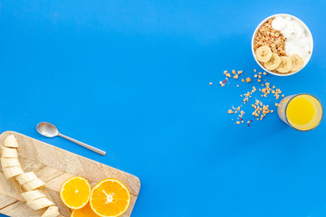 food for healthy breakfast with granola and fresh orange juice on bright blue background top view...