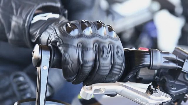 Closeup of a biker's hand. Biker twists the Handle of the Gas on the Wheel of the Motorcycle