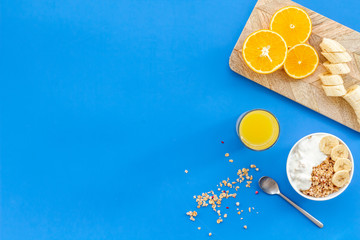 food for healthy breakfast with granola and fresh orange juice on bright blue background top view mock up