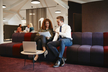 Two businesspeople discussing paperwork together on an office so