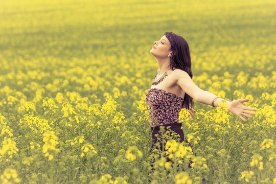 Happy beautiful woman in free summer love of youth wellbeing. Attractive young beauty girl enjoying the warm sunny sun in nature rapeseed field takes time feeling sustainability and contemplation