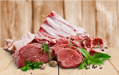 Fresh raw meat with vegetables on brown wooden table at wooden background