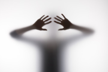 Blurry silhouette of person touching glass with hands