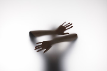 Blurry silhouette of person touching glass with hands