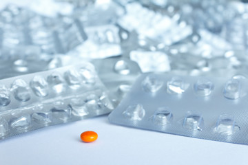 One single pill in front of many empty blister packages on white background, drug misuse concept