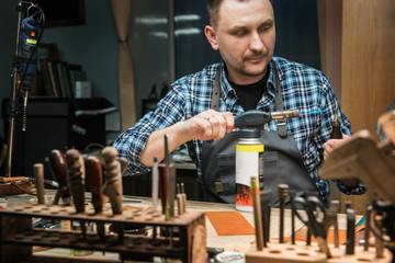 Man working with leather textile at a workshop. Concept of handmade craft production of leather goods.