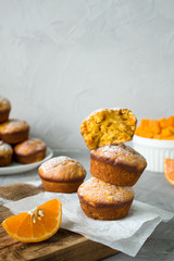 vegan dessert. sweet homemade muffins with pumpkin and orange and powdered sugar on a grey background. copy space. selective focus
