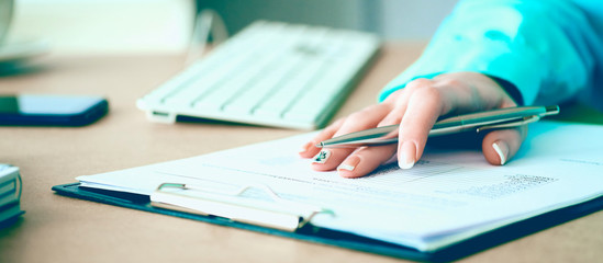 Hand of businesswoman filling and signing with silver pen partnership agreement form clipped to pad close-up. Management training course, some important document, team leader ambition concept