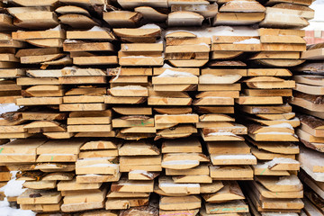 Folded wooden brown and gray planks in a sawmill. Piled alder boards as texture