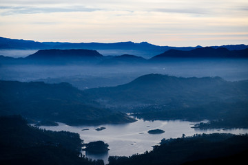 Blue landscape with mountains, lake and  morning fog. Cloudy sunrice