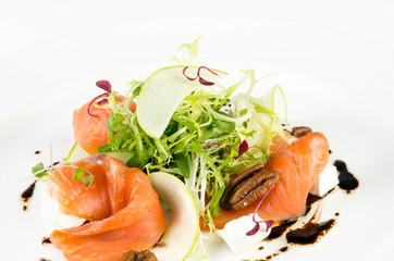 Marinated salmon with feta cheese, green apple, pecan and soy sauce on a plate on a white background