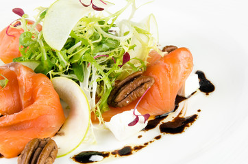 Marinated salmon with feta cheese, green apple, pecan and soy sauce on a plate on a white background