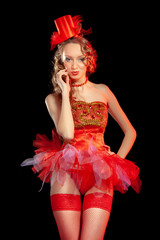 Sexy burlesque dancer stripper posing in red corset and red hat with curly hair and beautiful legs...