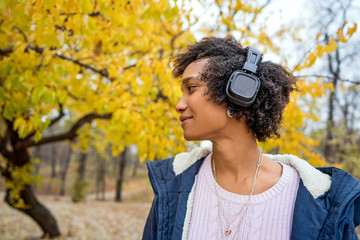 Afroamerican girl listening to music in the autumn at sunset