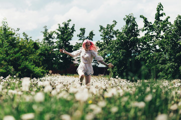 A girl runs across a field of dandelions in summer
