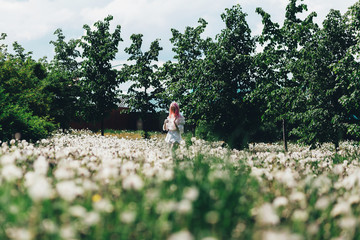 A girl runs across a field of dandelions in summer