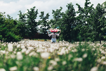 A girl runs across a field of dandelions in summer