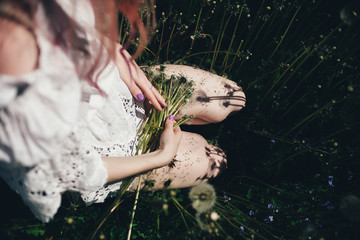 the girl sitting  in a high field with dandelions in the summer 