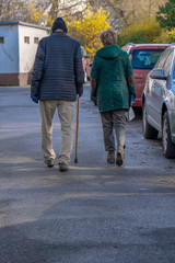 Älteres Ehepaar von hinten neben parkenden Autos