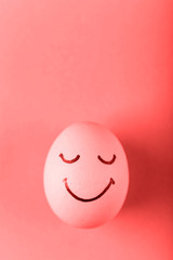Coral egg with painted smiles. Happy Easter concept greeting card design.