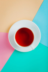 A cup of tea on a pastel colored paper background. Copy space.