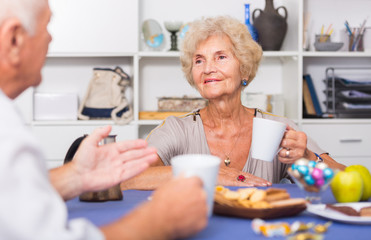 Smiling elderly woman drinking tea with husband
