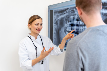 Zahnärztin erklärt Patient das Röntgenbild am großen Monitor