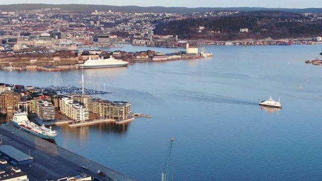 Aerial real time following the ferry boat shot near Aker Brygge seen towards Akershus and Bjorvika in Oslo, Norway in spring 2019