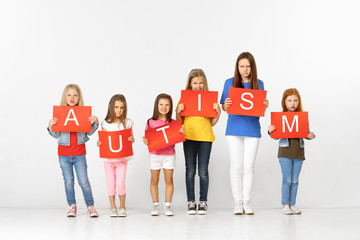 Obraz premium Autism - dont be scared to be different. Group of angry sad children with red banners isolated in white studio background. Education and advertising concept. Protest, rights and health concepts.