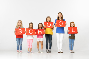 School of friendship. Group of happy smiling children and teenagers or friends with red banners making word isolated in white studio background. Young team. Education and advertising concept.