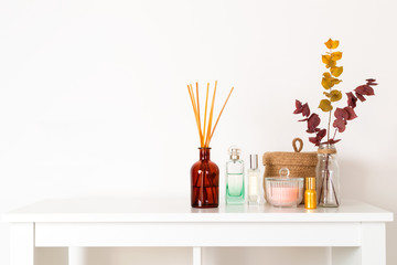 Scandinavian hygge style, home interior - aroma diffuser with wooden sticks, perfume, straw basket,...