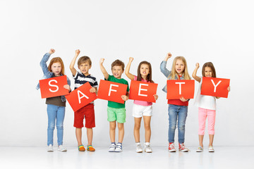 Fototapeta premium Safety feeling gives calm. Group of unhappy angry children with red banners isolated in white studio background. Education and advertising concept. Protest and children's rights concepts.