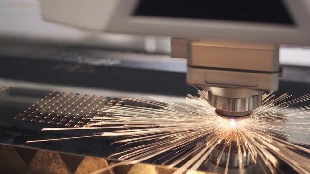 Metal processing. Cut sheet metal. Industrial machine CNC plasma laser cutter indoors. Flying sparks. Automation of sheet metal cutting process. Modern tools in engineering. Closeup