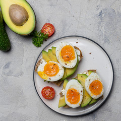 Sandwich on grain bread with boiled egg and avocado on plate