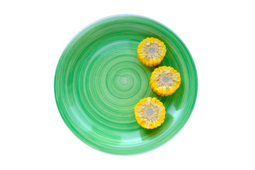 Corn in green round plate on white background. Cut into pieces corn. The view from the top. Menu design concept. Health, nutrition concept. Agriculture.