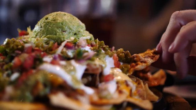 Person taking a snack from a nachos and cheese