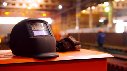 Construction plant. People working on the background. A black helmet on the foreground