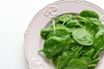 Young leaves of spinach on a plate. Copy space. Detox, a dietary food ingredient - green organic...