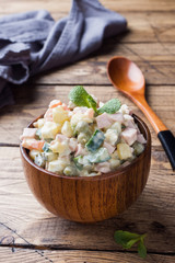 Traditional Russian Christmas and New year salad Olivier in wooden bowl. Selective focus