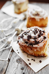 Cinnamon rolls with cream cheese and chocolate chips  on wooden background
