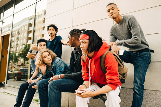 Male friends spending leisure time at sidewalk in city
