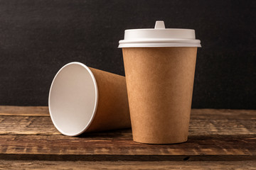 Disposable cup from Kraft on a wooden table with copy space. Black Background, mockup